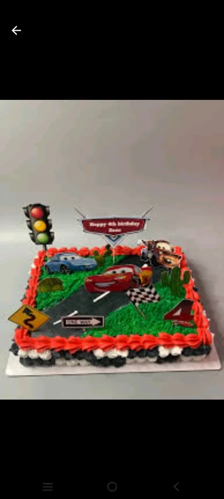 Disney Cars themed square cake with Lightning McQueen and Mater printouts on a green grass and road icing design. Disney Cars themed square cake with Lightning McQueen and Mater printouts on a green grass and road icing design.