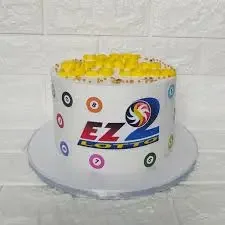 White EZ2 Lotto themed cake with colorful lottery ball graphics and yellow icing dollops on top. White EZ2 Lotto themed cake with colorful lottery ball graphics and yellow icing dollops on top.