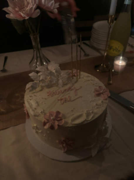 Elegant white 1-tier cake with pink and white gumpaste flowers, gold candles, and pink icing text. Elegant white 1-tier cake with pink and white gumpaste flowers, gold candles, and pink icing text.