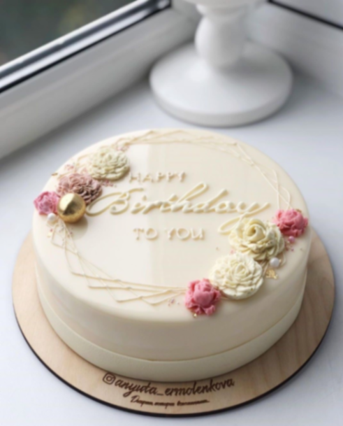 Elegant white mirror glaze cake with piped icing flowers in pink and cream, featuring a gold Happy Birthday message. Elegant white mirror glaze cake with piped icing flowers in pink and cream, featuring a gold Happy Birthday message.