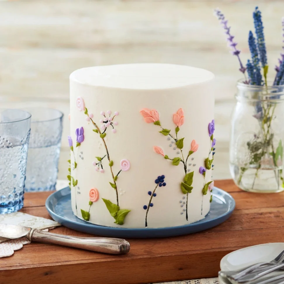 Floral Minimalist White Cake White 1 tier cake with smooth soft icing, Floral Minimalist theme, and delicate piped floral vines on the side