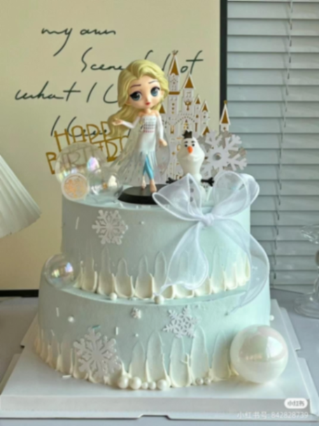 Frozen-Inspired Princess 2-Tier Birthday Cake Light blue two tier soft icing birthday cake with Elsa and Olaf figurines castle topper and sheer white bow