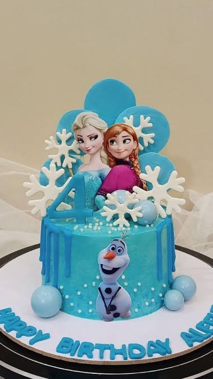 Blue Frozen themed birthday cake featuring Elsa, Anna, and Olaf printouts with white snowflakes and blue icing drips. Blue Frozen themed birthday cake featuring Elsa, Anna, and Olaf printouts with white snowflakes and blue icing drips.
