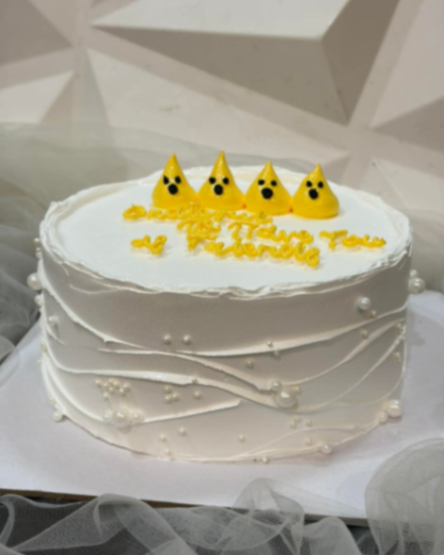 White minimalist cake with yellow ghost-like meringue toppers and yellow piped icing message. White minimalist cake with yellow ghost-like meringue toppers and yellow piped icing message.