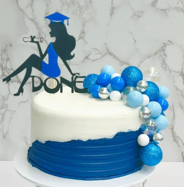A white and navy blue graduation cake with a silhouette topper of a graduate and a cluster of blue, white, and silver decorative balls. A white and navy blue graduation cake with a silhouette topper of a graduate and a cluster of blue, white, and silver decorative balls.