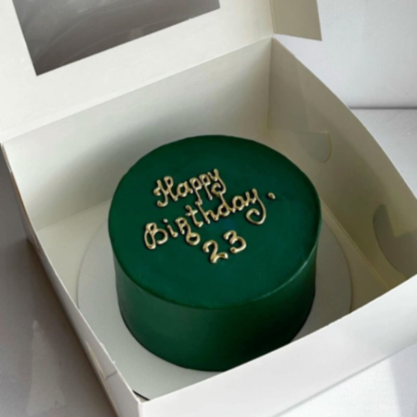 Minimalist dark green birthday cake with elegant gold piped icing message Happy Birthday 23.