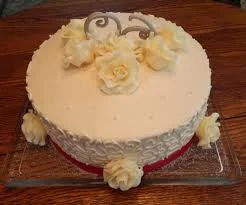 Elegant ivory one-tier cake with ivory gumpaste roses and silver scroll accents on a red ribbon base. Elegant ivory one-tier cake with ivory gumpaste roses and silver scroll accents on a red ribbon base.