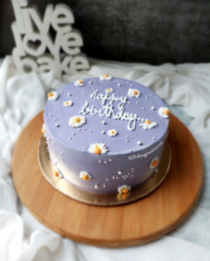 Minimalist lavender purple birthday cake with white piped icing daisies and 'happy birthday' message. Minimalist lavender purple birthday cake with white piped icing daisies and 'happy birthday' message.