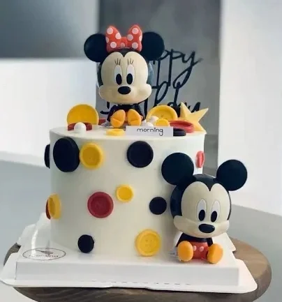 White 1-tier Mickey and Minnie Mouse themed birthday cake with colorful fondant buttons and 3D character figures. White 1-tier Mickey and Minnie Mouse themed birthday cake with colorful fondant buttons and 3D character figures.