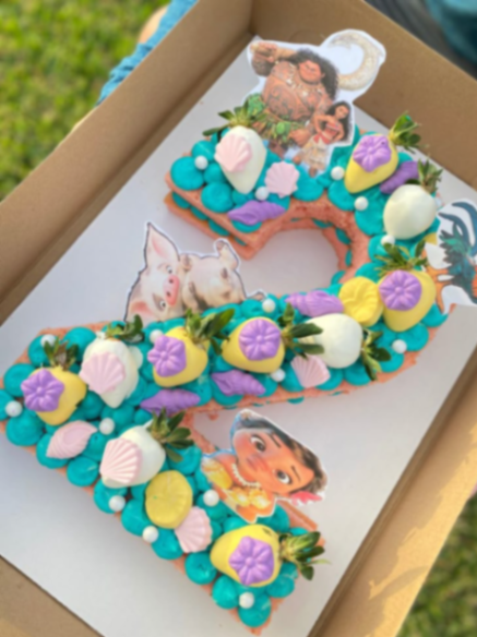 Teal number two cake with Moana character printouts, chocolate covered strawberries, and fondant seashells Teal number two cake with Moana character printouts, chocolate covered strawberries, and fondant seashells