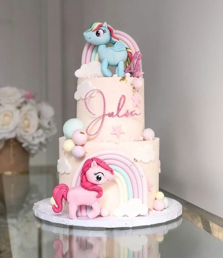 Two-tier pastel pink My Little Pony themed cake with 3D fondant ponies, rainbows, and clouds. Two-tier pastel pink My Little Pony themed cake with 3D fondant ponies, rainbows, and clouds.
