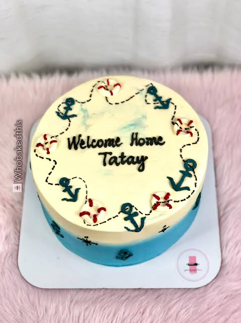 A nautical themed welcome home cake for Tatay featuring anchors and lifebuoys on a blue and white gradient icing.