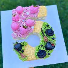 Number 5 shaped cake with pink and green icing, chocolate covered strawberries, and witch-themed decorations. Number 5 shaped cake with pink and green icing, chocolate covered strawberries, and witch-themed decorations.