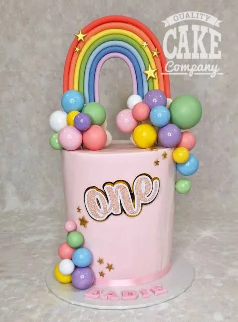Pastel Rainbow Pink Glitter Cake Pink 1-tier cake with soft icing finish, pastel rainbow theme, fondant rainbow arch, and glitter cardstock one topper