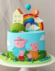 Light blue Peppa Pig themed birthday cake with fondant rainbow, house, and character figures on a green grassy base. Light blue Peppa Pig themed birthday cake with fondant rainbow, house, and character figures on a green grassy base.