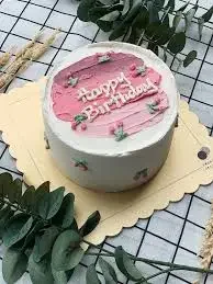 White minimalist birthday cake with pink palette knife icing and cherry decorations on top. White minimalist birthday cake with pink palette knife icing and cherry decorations on top.