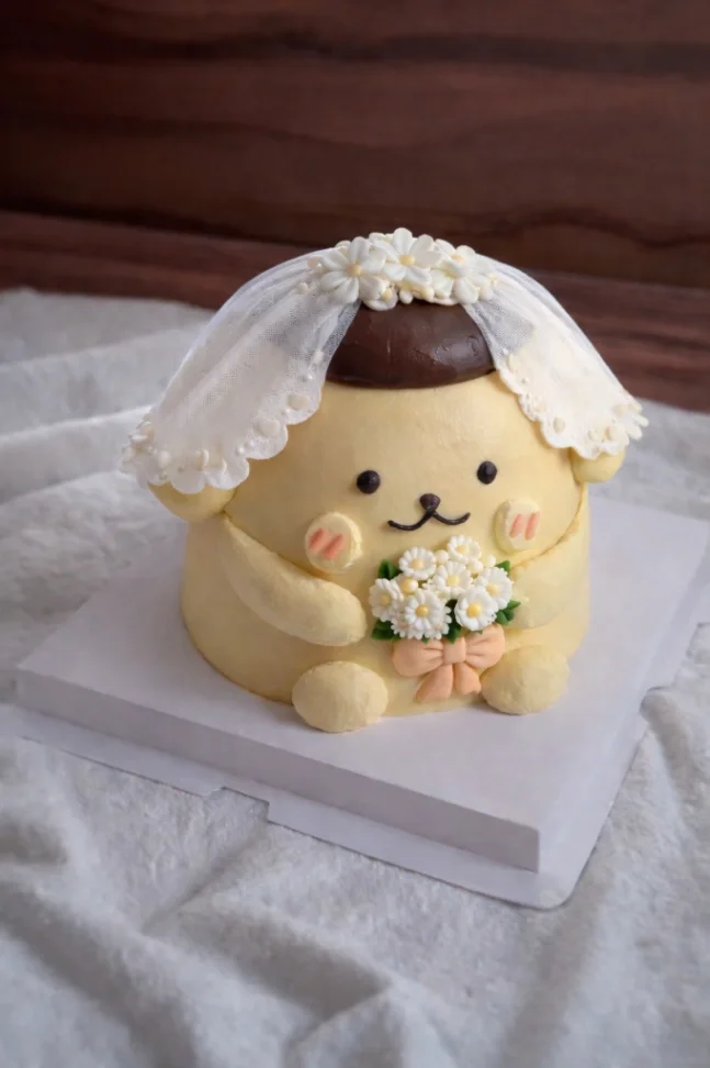 Pompompurin character cake shaped like a bride with a white lace veil and a bouquet of daisies. Pompompurin character cake shaped like a bride with a white lace veil and a bouquet of daisies.