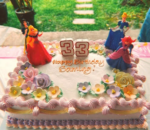 Princess Birthday White Floral Rectangle Cake White rectangular soft icing birthday cake decorated with plastic princess figurines number candles and pastel sugar flowers