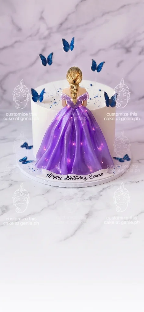 White single tier cake featuring a princess in a purple light-up gown with blue butterfly toppers and a Happy Birthday Emma banner.