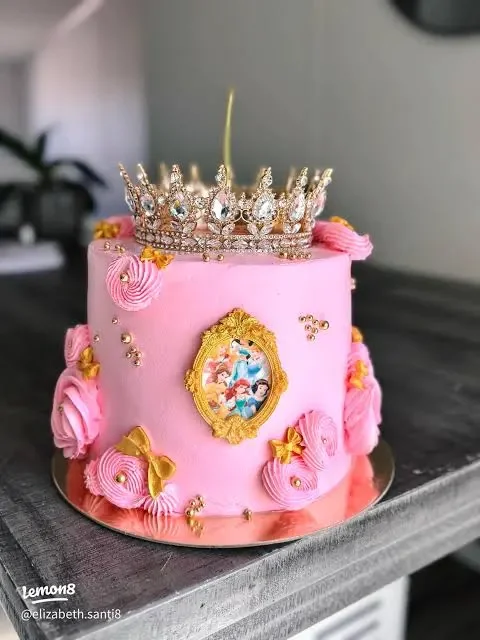 Princess Pink Crown Birthday Cake Pink 1-tier birthday cake with soft icing finish, a large gold rhinestone crown topper, and princess portrait print