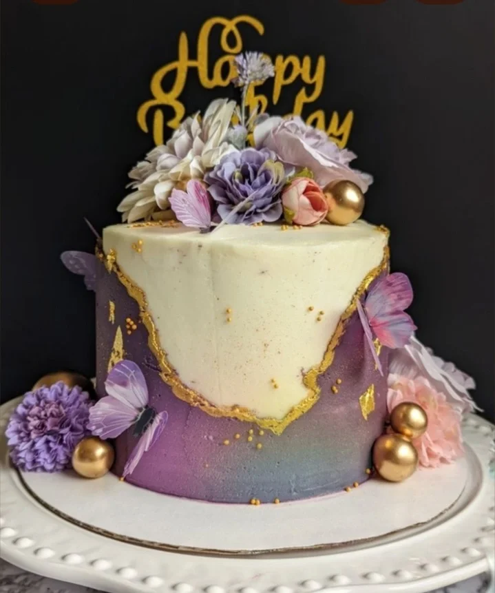 Elegant purple and white fault line cake decorated with purple butterflies, gold spheres, and a variety of silk and edible flowers. Elegant purple and white fault line cake decorated with purple butterflies, gold spheres, and a variety of silk and edible flowers.
