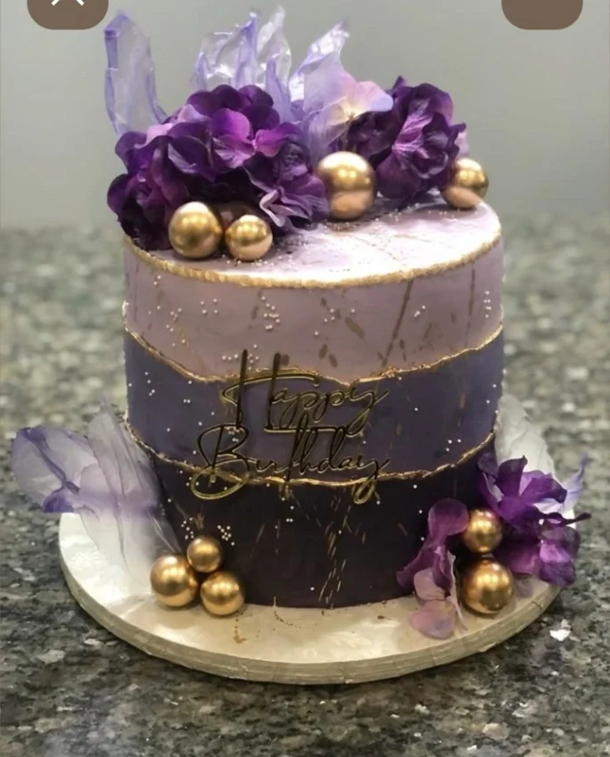 Elegant purple ombre birthday cake with gold accents, purple flowers, and gold spheres. Elegant purple ombre birthday cake with gold accents, purple flowers, and gold spheres.