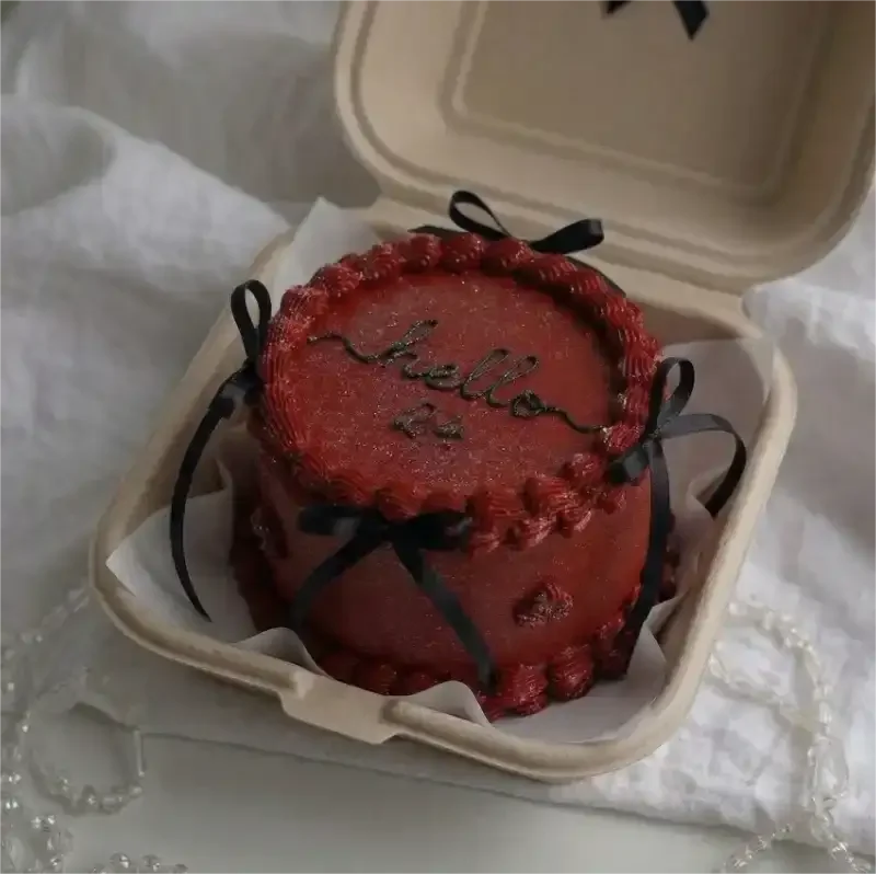 Dark red minimalist bento cake with black piped icing text and small black satin bows in a clamshell box. Dark red minimalist bento cake with black piped icing text and small black satin bows in a clamshell box.