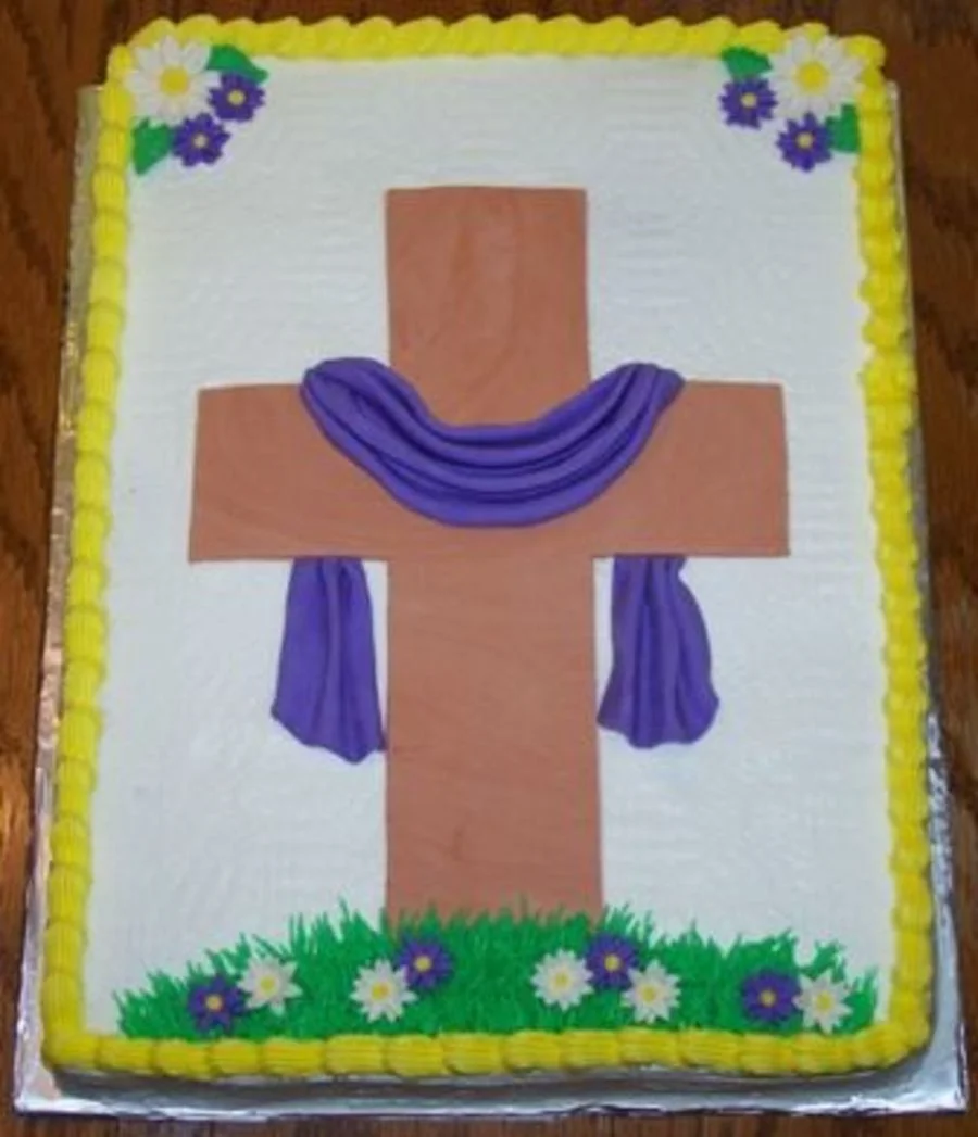 Rectangular white icing cake featuring a large brown cross with a purple draped cloth, green grass, and small white and purple flowers. Rectangular white icing cake featuring a large brown cross with a purple draped cloth, green grass, and small white and purple flowers.