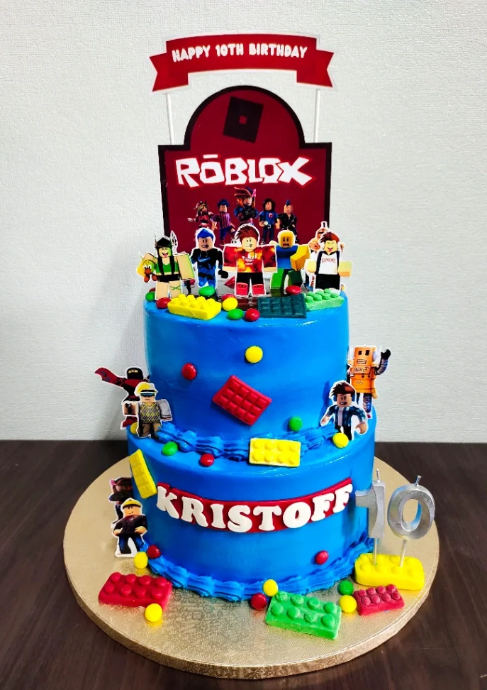 Blue 2-tier Roblox themed birthday cake with edible Lego bricks and character printouts for Kristoff's 10th birthday. Blue 2-tier Roblox themed birthday cake with edible Lego bricks and character printouts for Kristoff's 10th birthday.