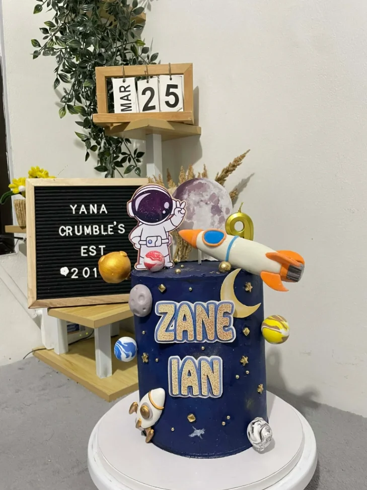Tall navy blue space themed cake with astronaut, rocket, and planet toppers for Zane Ian's birthday. Tall navy blue space themed cake with astronaut, rocket, and planet toppers for Zane Ian's birthday.