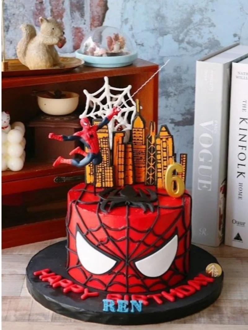 Spiderman-Inspired Birthday Cake Red 1-tier soft icing birthday cake with Spiderman theme, city skyline printout, and black web piping
