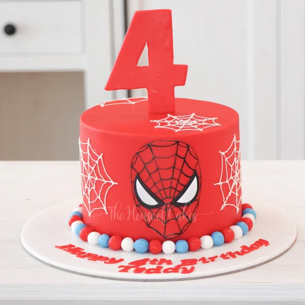 Spiderman-Inspired Birthday Cake Red fondant 1-tier birthday cake with a Spiderman face plaque, white piped spiderwebs, and a red number four topper