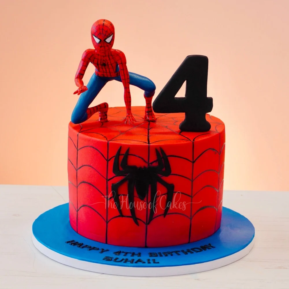 Spiderman-Inspired Birthday Cake Red fondant 1-tier birthday cake with a Spiderman figurine, number four topper, and web design