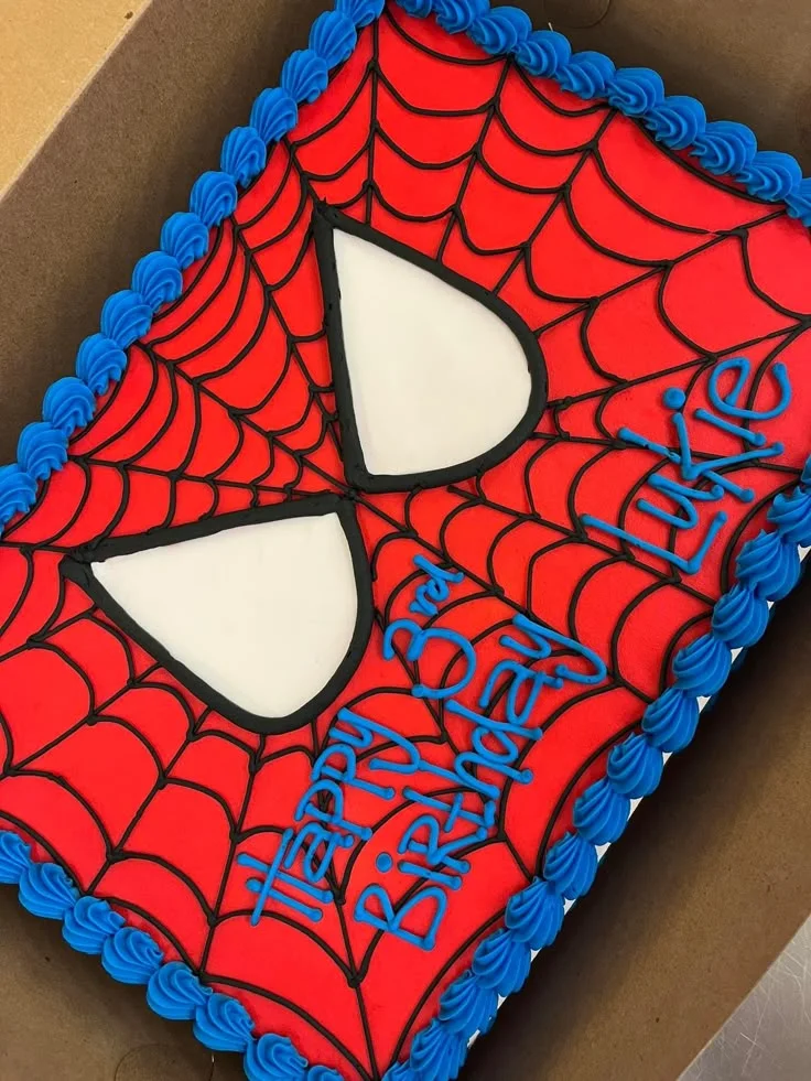 Spiderman-Inspired Rectangle Birthday Cake Red rectangular soft icing cake with black web lines, white eyes, blue piped borders, and blue piped birthday message