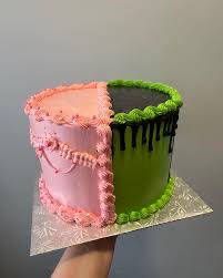 A split-design cake with one half in pink ruffled icing and the other half in green smooth icing with black chocolate drips. A split-design cake with one half in pink ruffled icing and the other half in green smooth icing with black chocolate drips.
