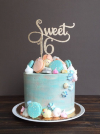 Light blue textured 1-tier cake for a Sweet 16 celebration featuring a gold glitter topper, macarons, and meringue kisses. Light blue textured 1-tier cake for a Sweet 16 celebration featuring a gold glitter topper, macarons, and meringue kisses.