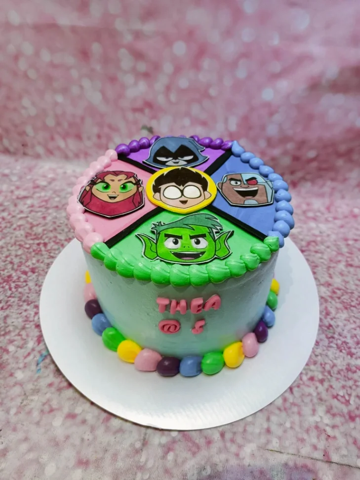 Teen Titans Go themed birthday cake with light blue icing and character printouts of Robin, Starfire, Raven, Cyborg, and Beast Boy. Teen Titans Go themed birthday cake with light blue icing and character printouts of Robin, Starfire, Raven, Cyborg, and Beast Boy.