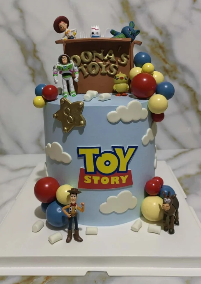 Toy Story-Inspired Sky Blue Birthday Cake Light blue 1-tier birthday cake with soft icing, Toy Story logo, character figurines, and colorful plastic spheres