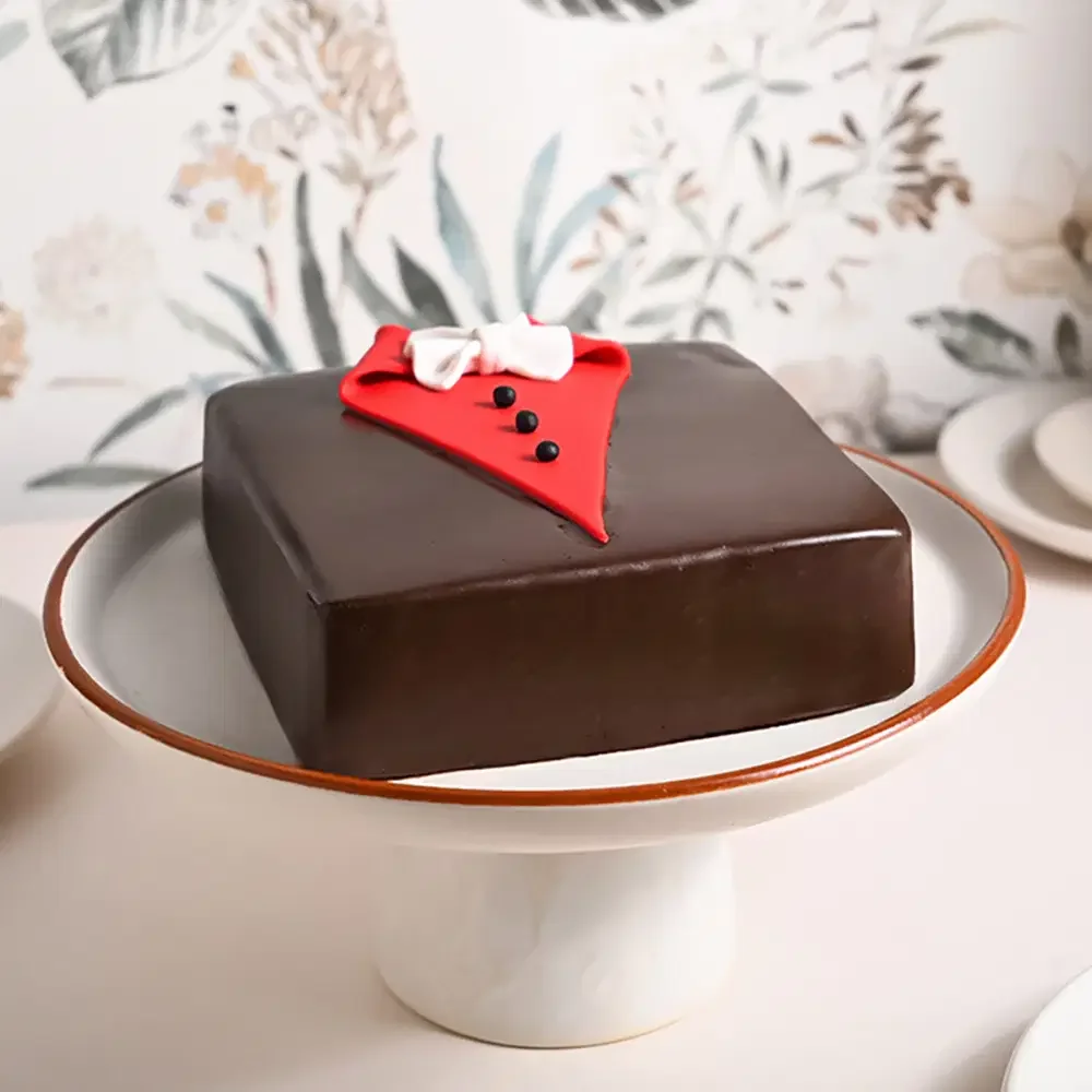 Square chocolate cake designed like a tuxedo with a red gumpaste shirt front, black buttons, and a white bow tie. Square chocolate cake designed like a tuxedo with a red gumpaste shirt front, black buttons, and a white bow tie.