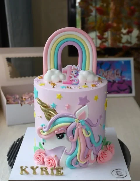 Tall pink unicorn birthday cake with a large fondant rainbow topper, 3D unicorn face, and pink icing roses at the base. Tall pink unicorn birthday cake with a large fondant rainbow topper, 3D unicorn face, and pink icing roses at the base.