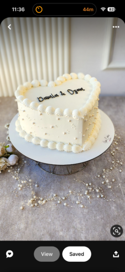 White heart-shaped minimalist cake with elegant piped borders and pearl accents. White heart-shaped minimalist cake with elegant piped borders and pearl accents.
