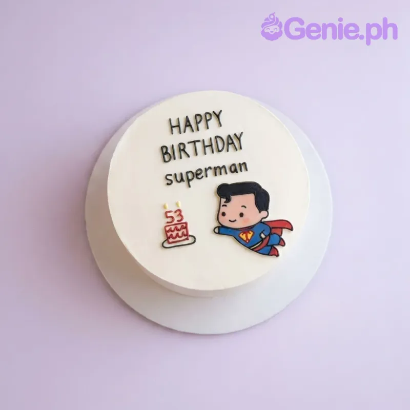 White round cake with smooth icing featuring a Superman character printout, a number 53 cake graphic, and Happy Birthday Superman text. White round cake with smooth icing featuring a Superman character printout, a number 53 cake graphic, and Happy Birthday Superman text.