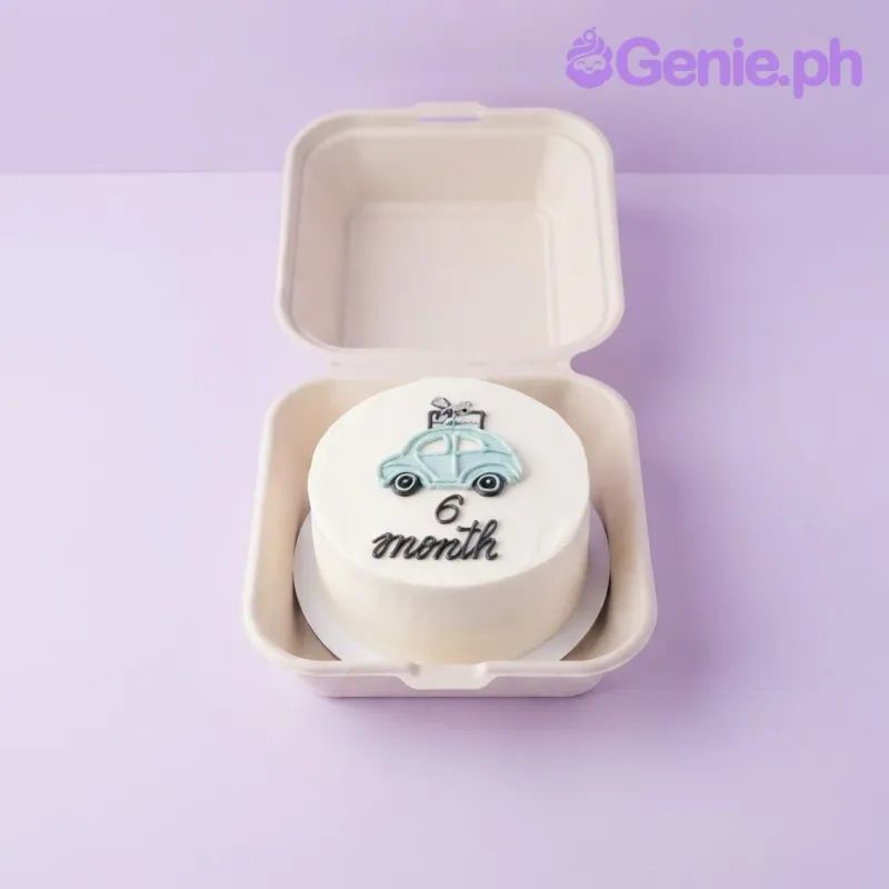 White bento cake with a light blue car topper and black piped 6 month message White bento cake with a light blue car topper and black piped 6 month message