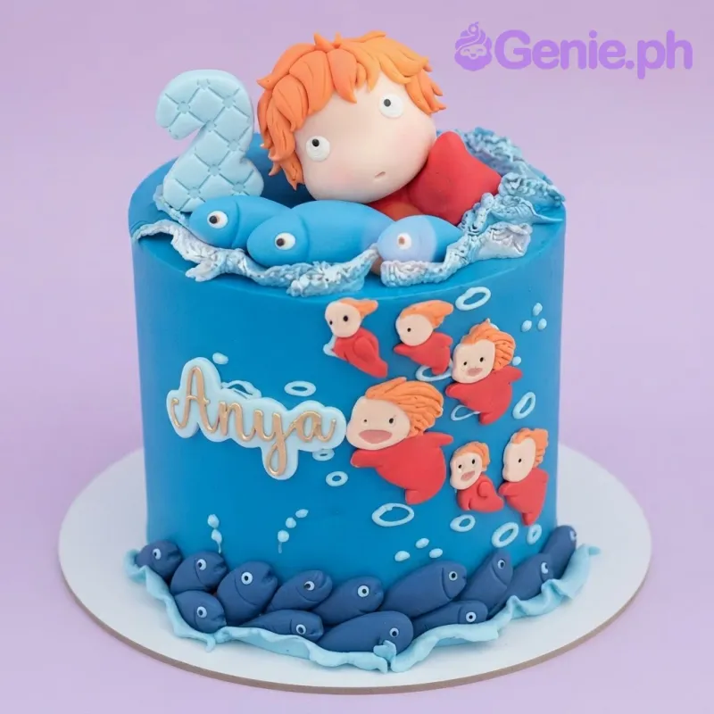 Blue fondant cake featuring a Ponyo character topper, small fish decorations, and a name plaque for Anya Blue fondant cake featuring a Ponyo character topper, small fish decorations, and a name plaque for Anya