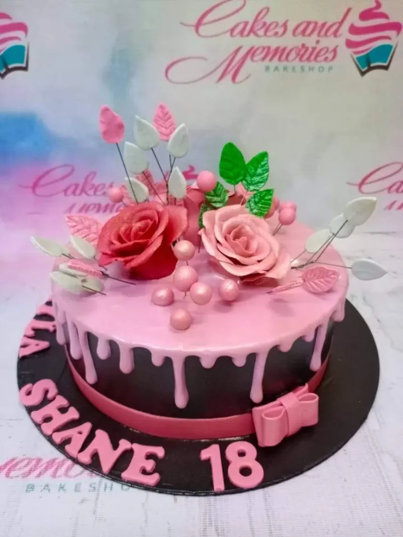 A pink and black 1-tier 18th Birthday cake, featuring edible pink and red roses, a pink drip, and a pink fondant bow. A pink and black 1-tier 18th Birthday cake, featuring edible pink and red roses, a pink drip, and a pink fondant bow.