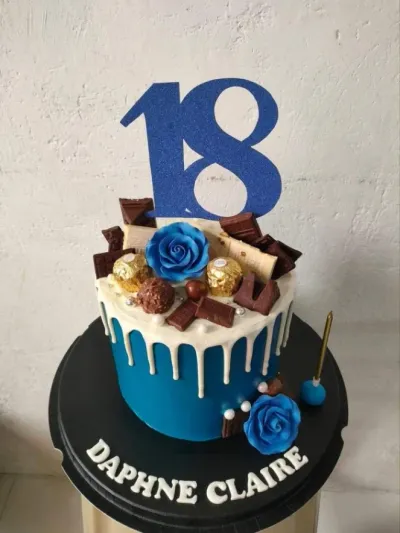 A blue and white 1-tier cake themed around 18th Birthday, featuring a blue glitter number 18 and white chocolate drip. A blue and white 1-tier cake themed around 18th Birthday, featuring a blue glitter number 18 and white chocolate drip.