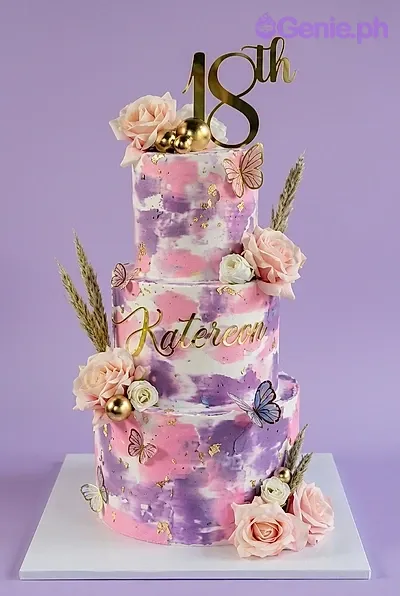 A white, pink, and purple 3-tier 18th birthday watercolor cake with a gold '18th' topper, peach roses, and butterflies. A white, pink, and purple 3-tier 18th birthday watercolor cake with a gold '18th' topper, peach roses, and butterflies.