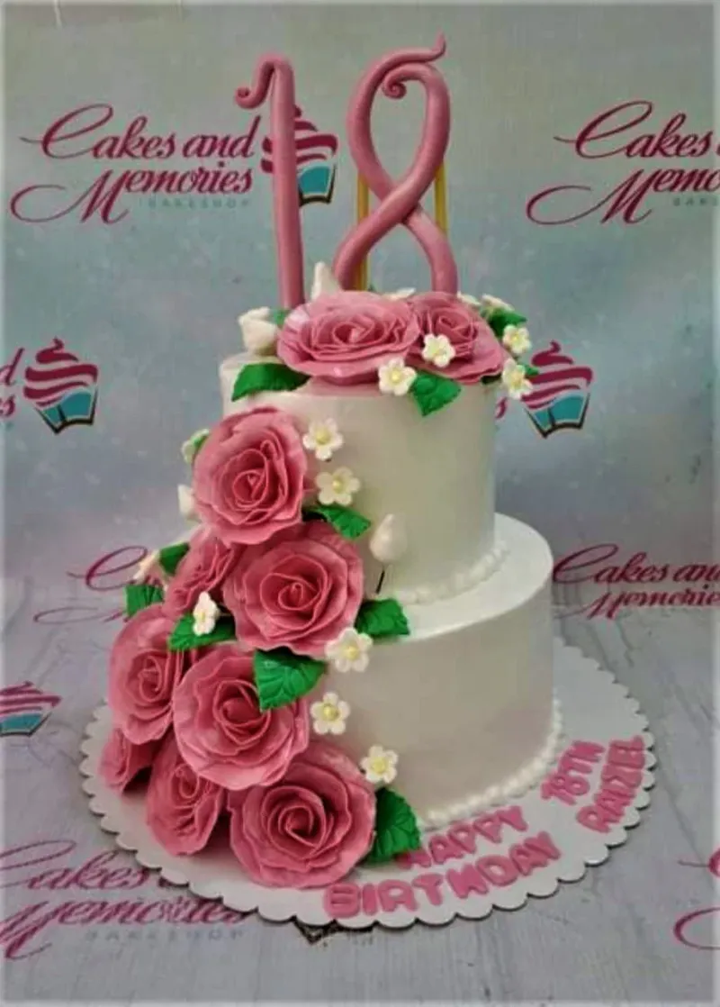 A white 2-tier 18th Birthday cake, featuring a large pink number 18 topper and pink gumpaste roses. A white 2-tier 18th Birthday cake, featuring a large pink number 18 topper and pink gumpaste roses.