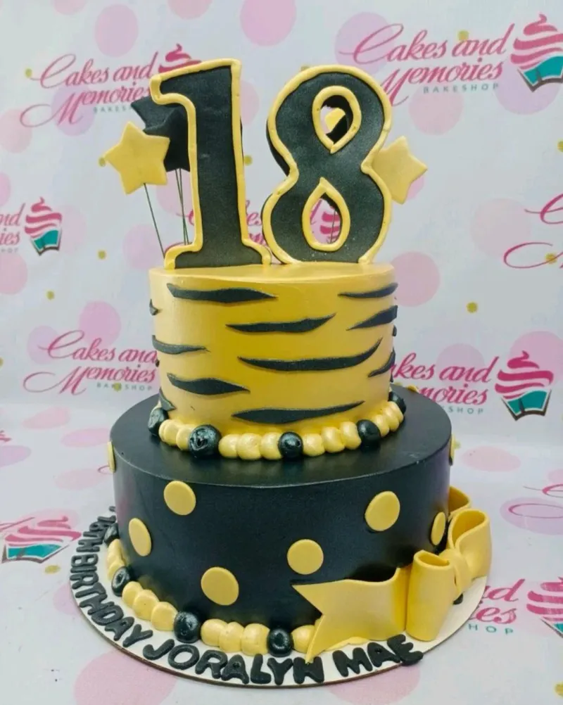 Two-tier black and yellow 18th birthday cake with tiger stripes, polka dots, and large number 18 toppers. Two-tier black and yellow 18th birthday cake with tiger stripes, polka dots, and large number 18 toppers.