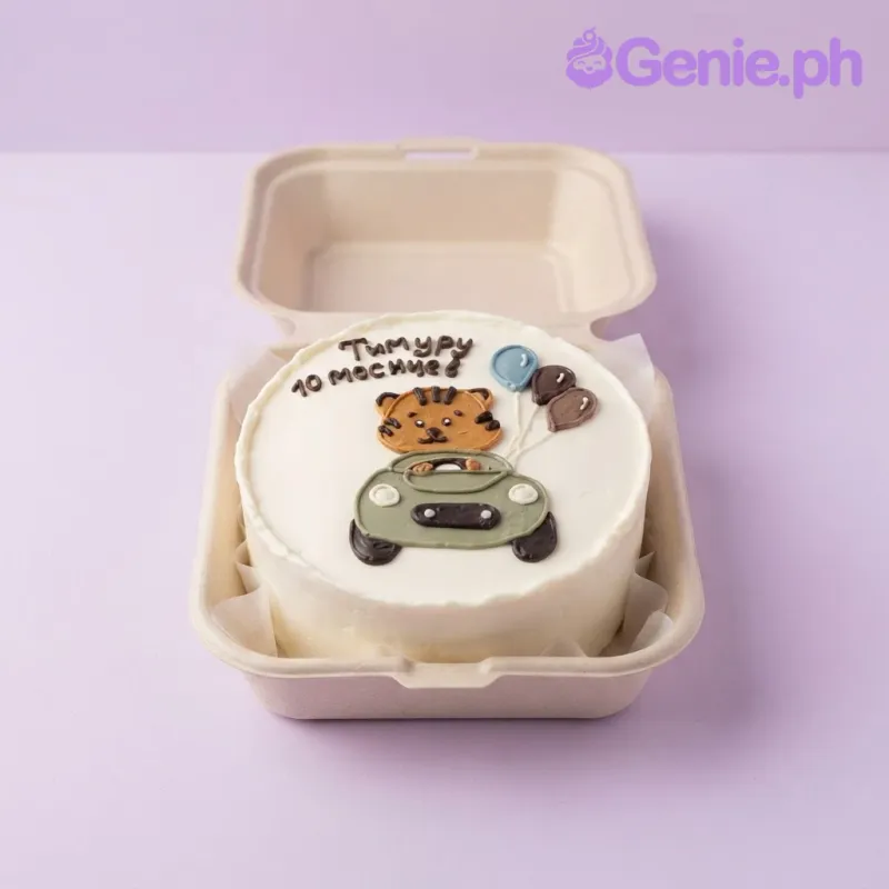 White bento cake with a hand-piped icing doodle of a tiger driving a car and three balloons, featuring Russian text on top. White bento cake with a hand-piped icing doodle of a tiger driving a car and three balloons, featuring Russian text on top.